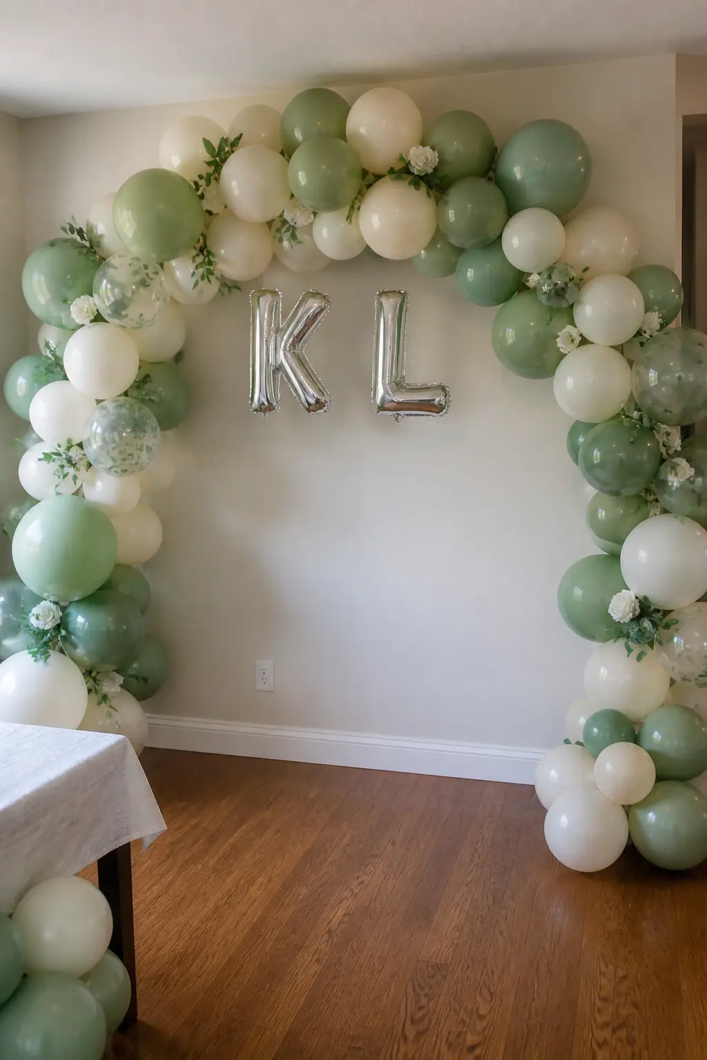 Sage and Cream Arch with the Bride's Initials at the Centre — A standing arch in sage and cream uses a mix of balloon sizes, with the largest ones clustered at