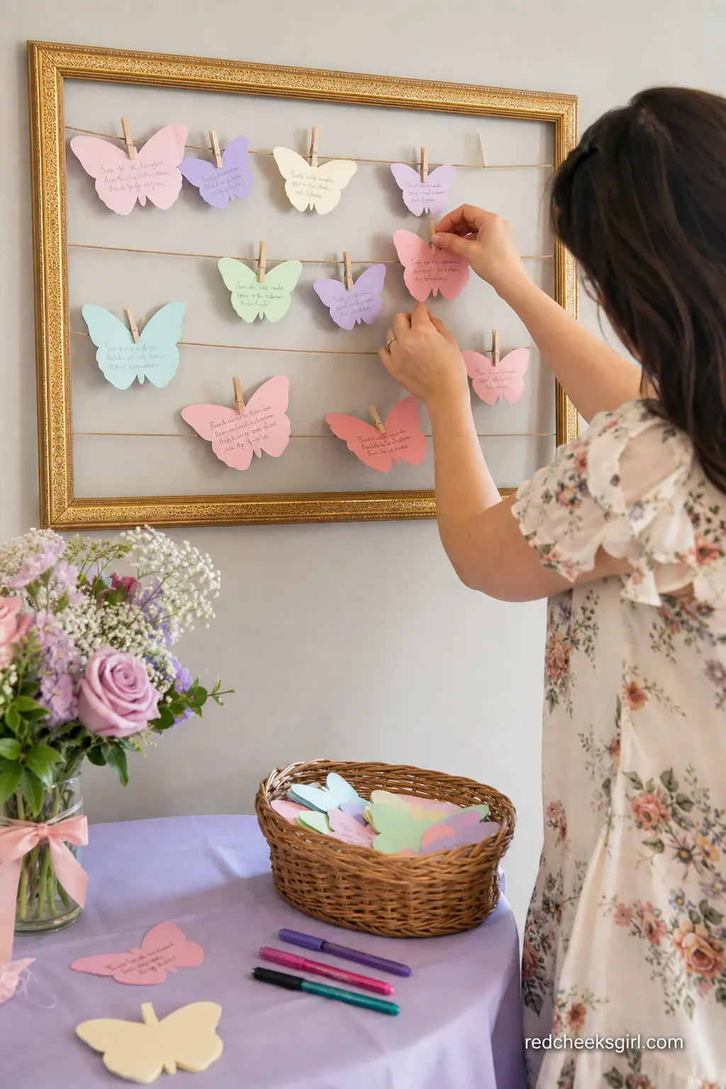 Butterfly Wishes Frame Keepsake Station — A gold frame strung with twine, a small basket of pastel paper butterfly cutouts and a cup of pens invites guests to