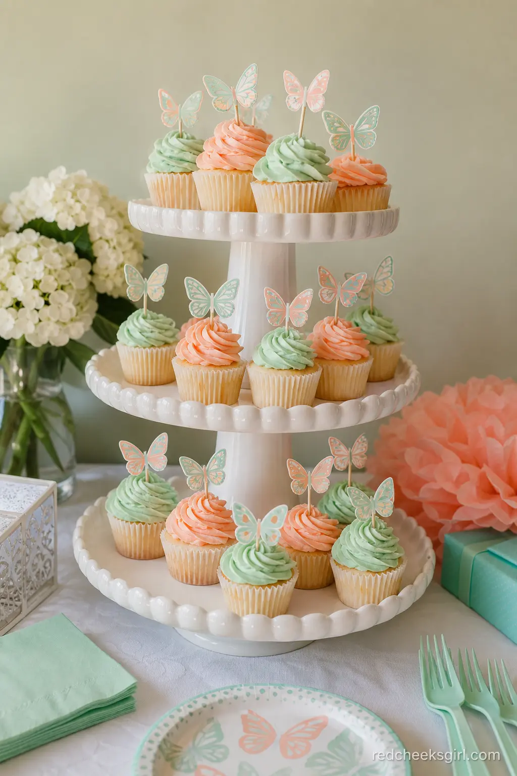 Peach and Mint Cupcake Tower — A tiered stand of cupcakes swapping between peach and mint frosting, topped with small paper butterfly picks, fills a lot of