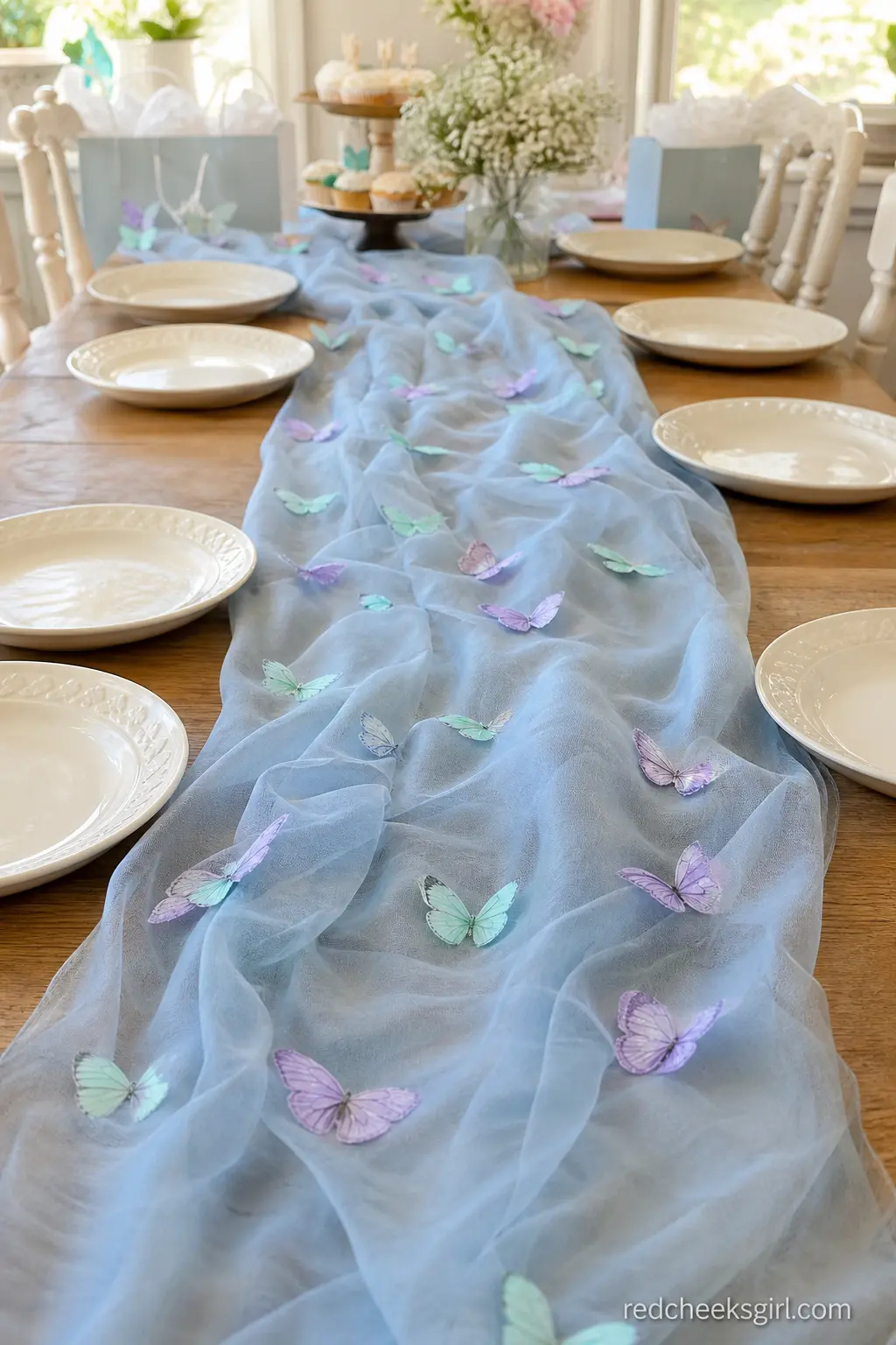 Sheer Butterfly-Scattered Table Runner — A sheer dusty blue runner down the center of a long table gives the whole surface a soft, floating look, especially
