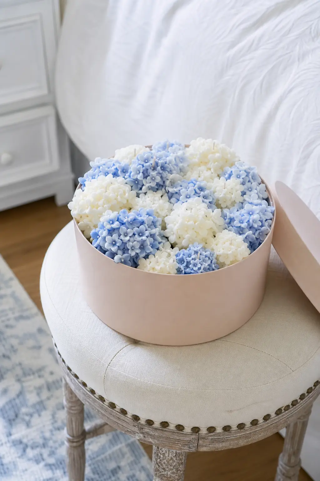 Hatbox Hydrangea — A cluster of tiny hydrangea-shaped candles in powder blue and white, packed close together inside a round blush hatbox so the finished piece