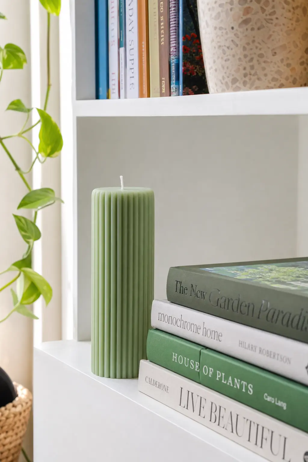 Fluted Ribbed Cylinder Pillar — A tall fluted cylinder in sage green looks architectural next to a stack of books, and eucalyptus fragrance keeps it from