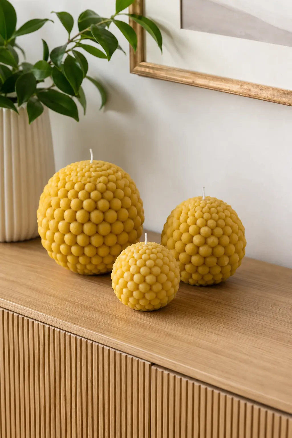 Graduated Bubble Sphere Trio — Three bubble spheres in mustard yellow, graduated from largest to smallest, group like a still life on a console table. Candle