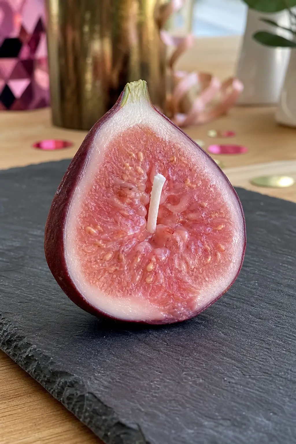Halved Fig Candle — A halved fig candle, deep burgundy skin opening onto a pink interior, is a more sophisticated fruit shape than a strawberry and suits a