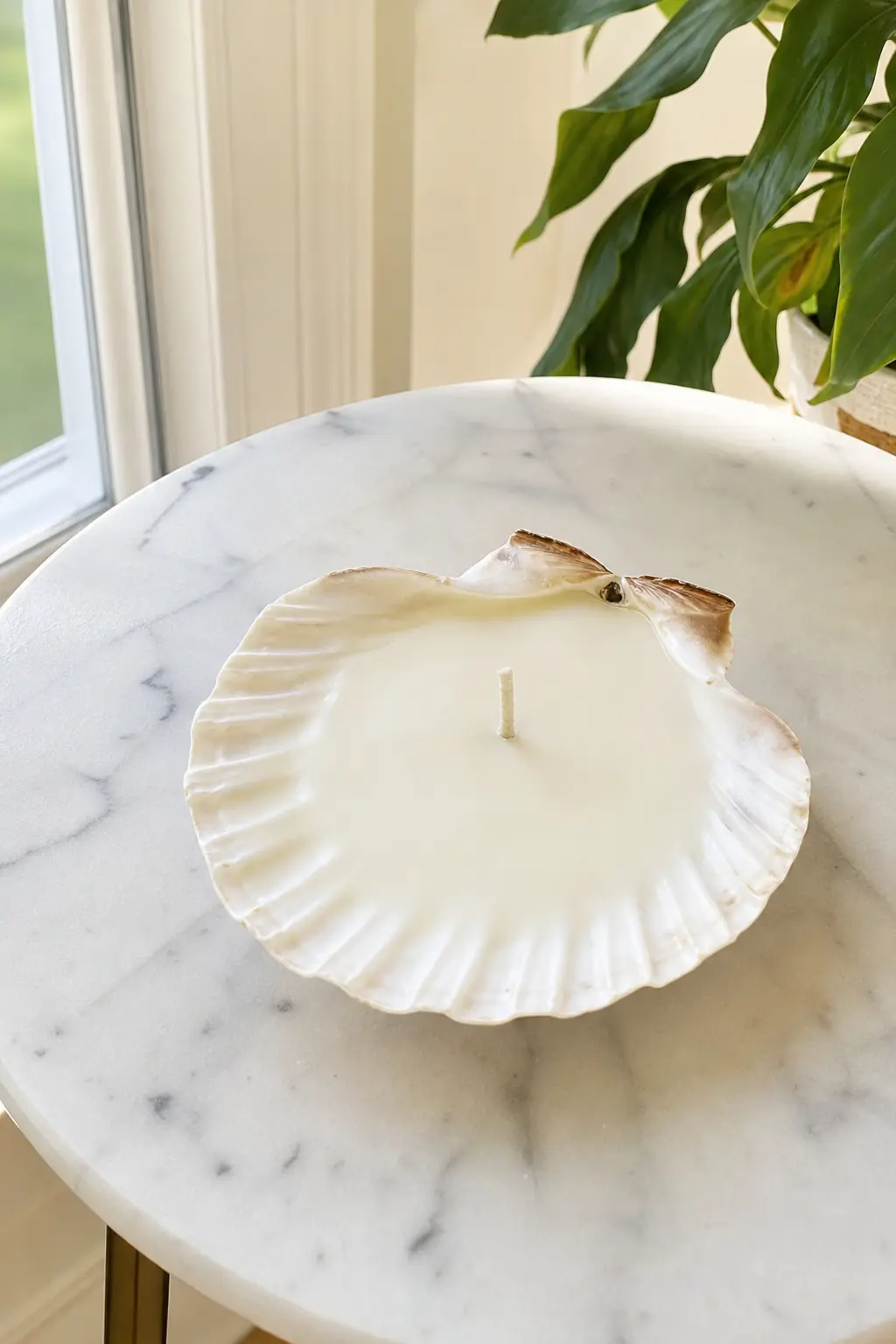 Scallop Shell Candle — A single large scallop shell filled with a cream wax candle needs almost no styling: the natural ridges do the decorative work on their