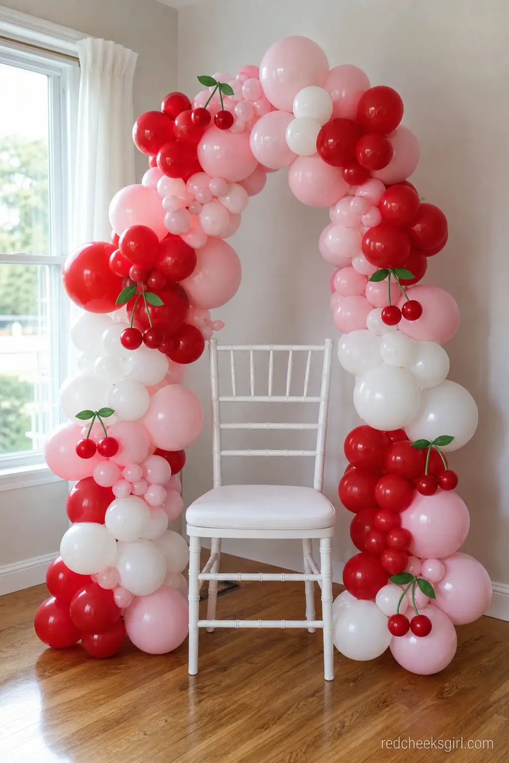 Balloon Garland Mama-to-Be Chair — A single white chair wrapped in a cherry red and blush balloon garland gives the guest of honor an obvious, photogenic seat