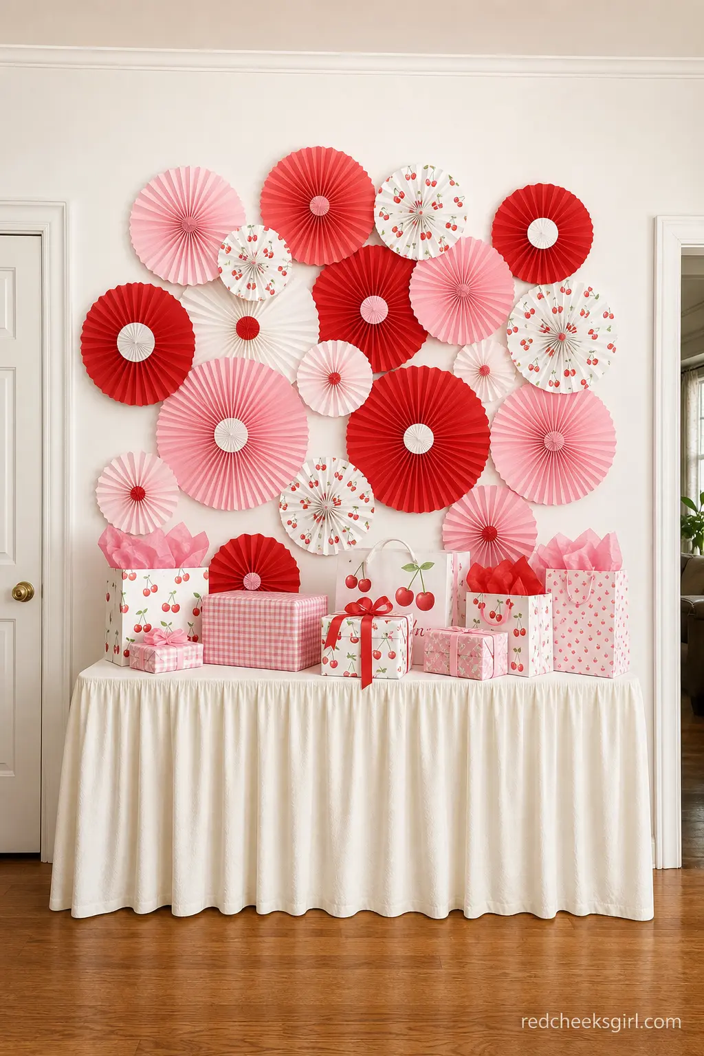 Cherry Paper Fan Gift Table Backdrop — A cluster of red, pink, and white paper fans behind the gift table gives it a clear visual boundary without a full
