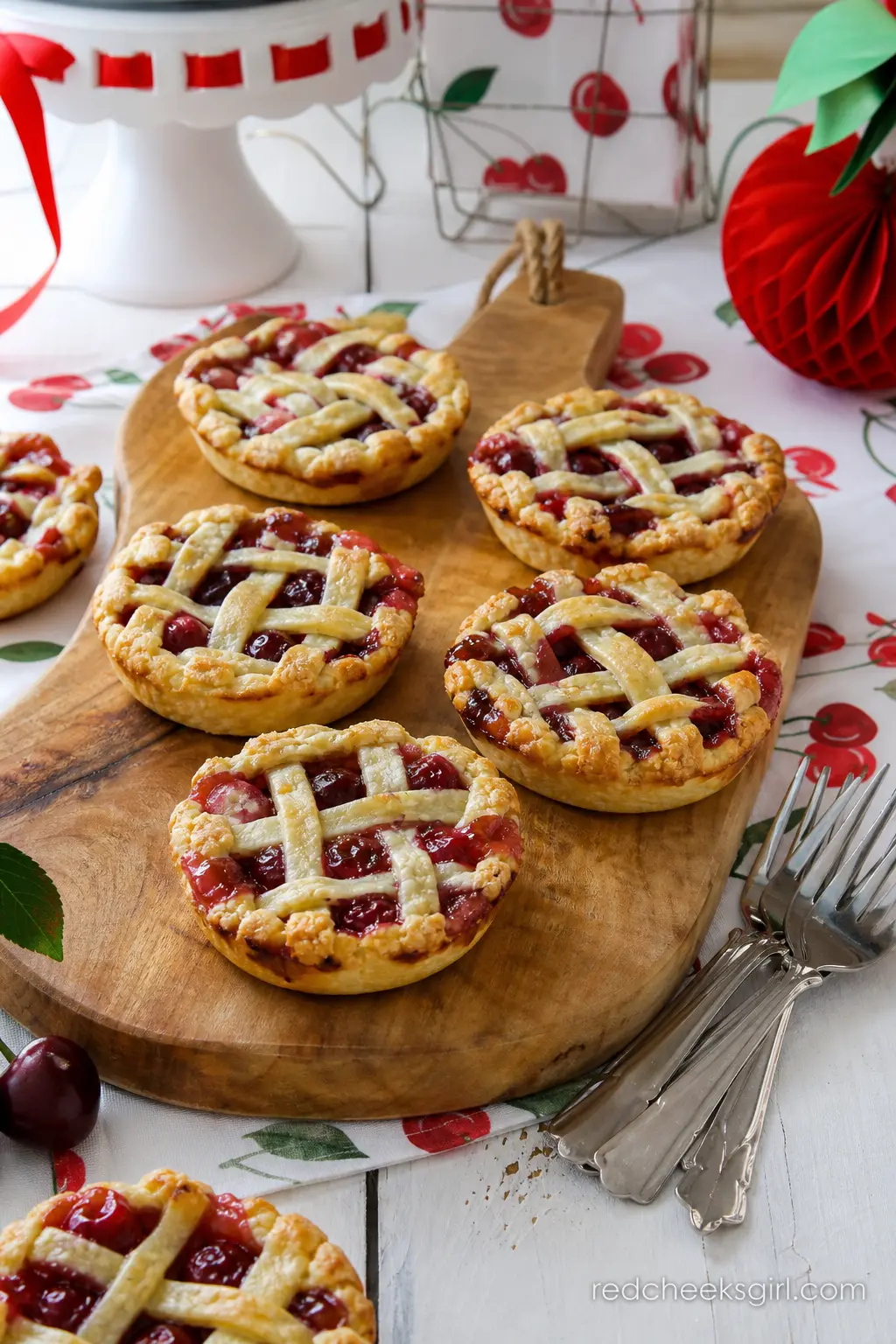 Mini Cherry Pies on a Rustic Board — Individual mini cherry pies with golden lattice tops and deep red filling bring a warm, homemade feel to the dessert