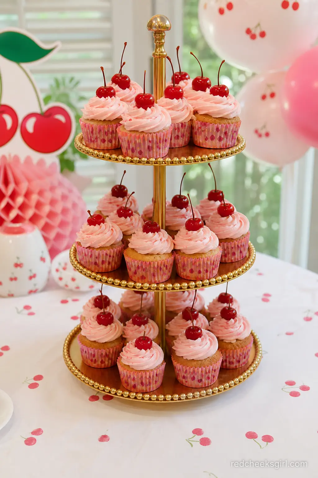 Pink Frosted Cupcake Tower — An assortment of cupcakes decorated with cherry accents adds variety and charm to the display. Cherry on top baby shower theme