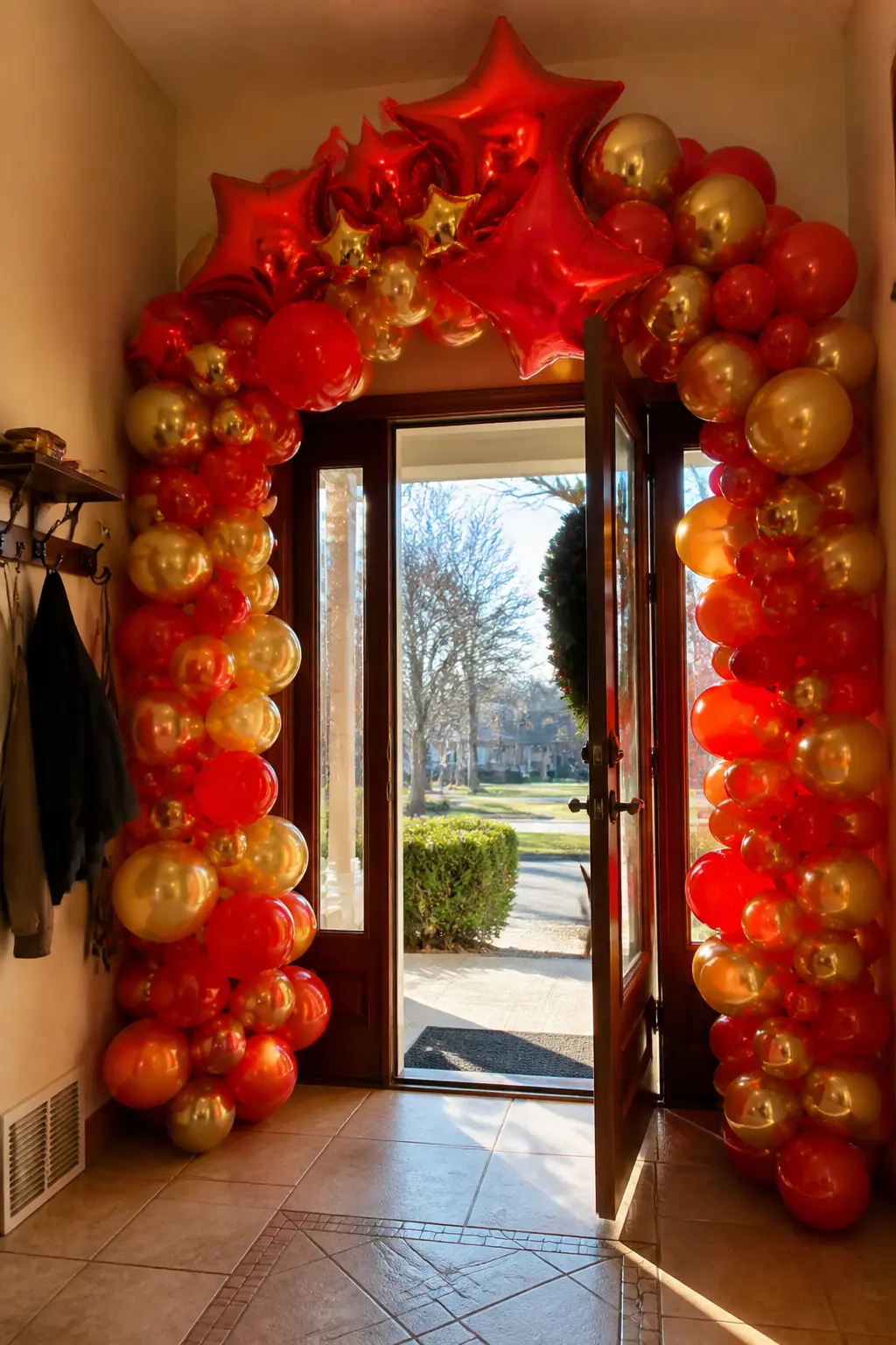The Red-and-Gold Front-Door Frame — Classic red and warm gold balloons arc over a front door that opens directly into a living room with a traditionally