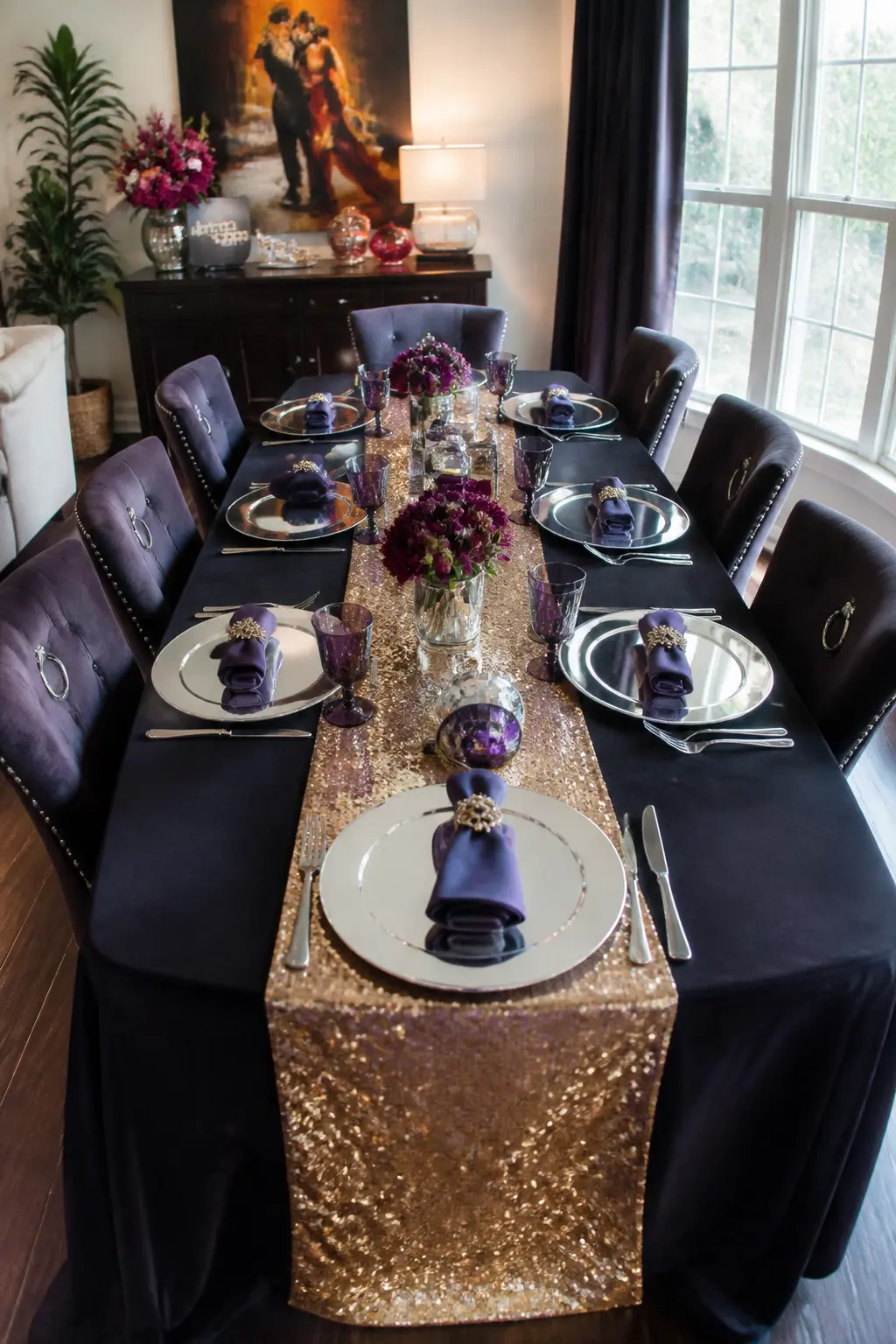 Sequined Table Runner With Mirrored Chargers — A gold sequin table runner down the centre of a dark-clothed dining table, with silver mirrored charger plates