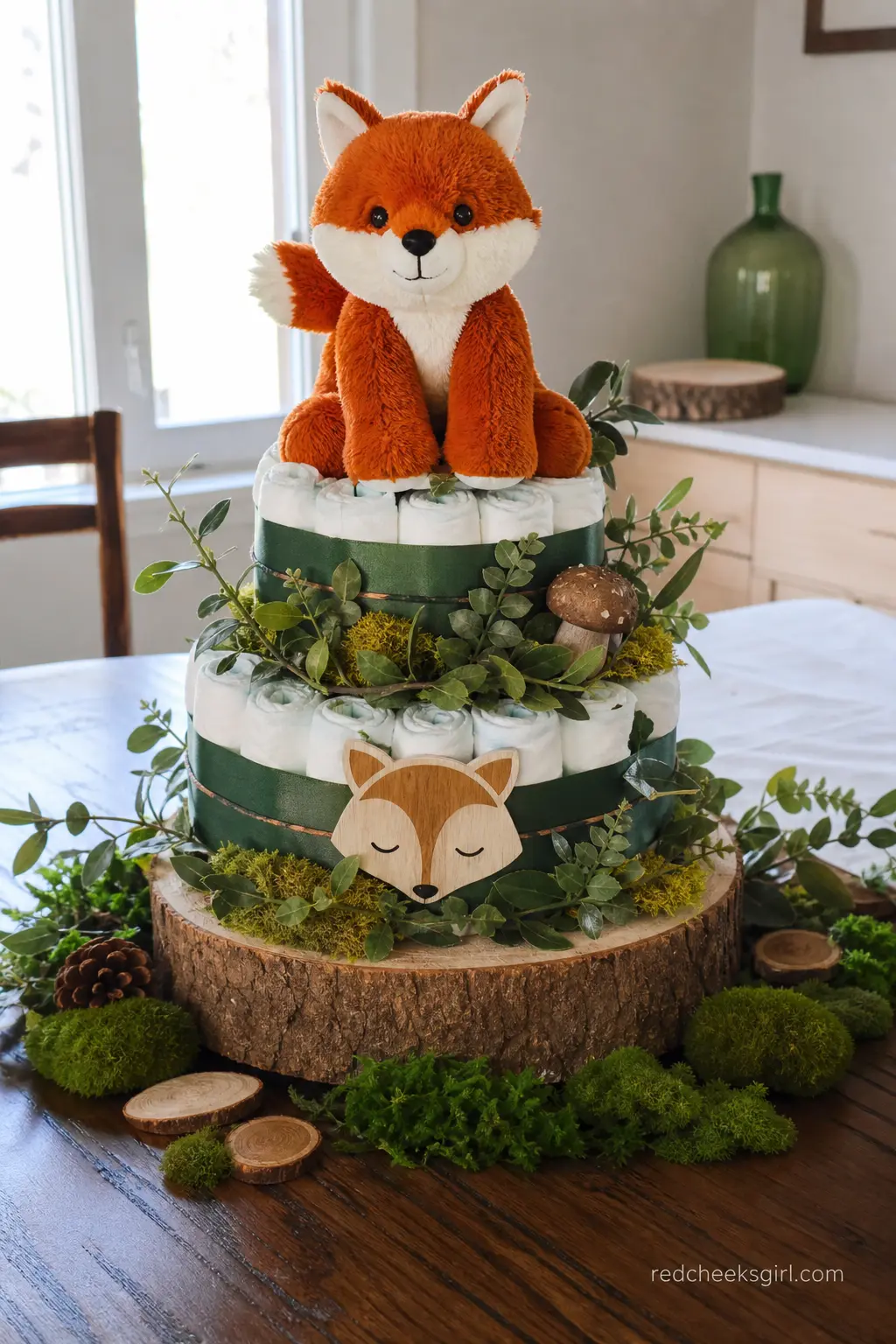 Woodland Fox Diaper Cake — Forest green ribbon and a rust coloured fox topper sit on a slice of real tree stump instead of a cake board, with a touch of faux
