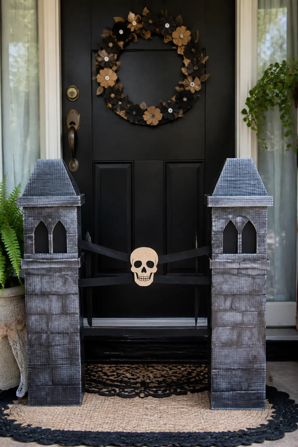 Wreath-Frame Graveyard Gate — Cut two tall gate-post shapes from corrugated board and paint them in stone grey, dry-brushed with white to suggest aged granite.