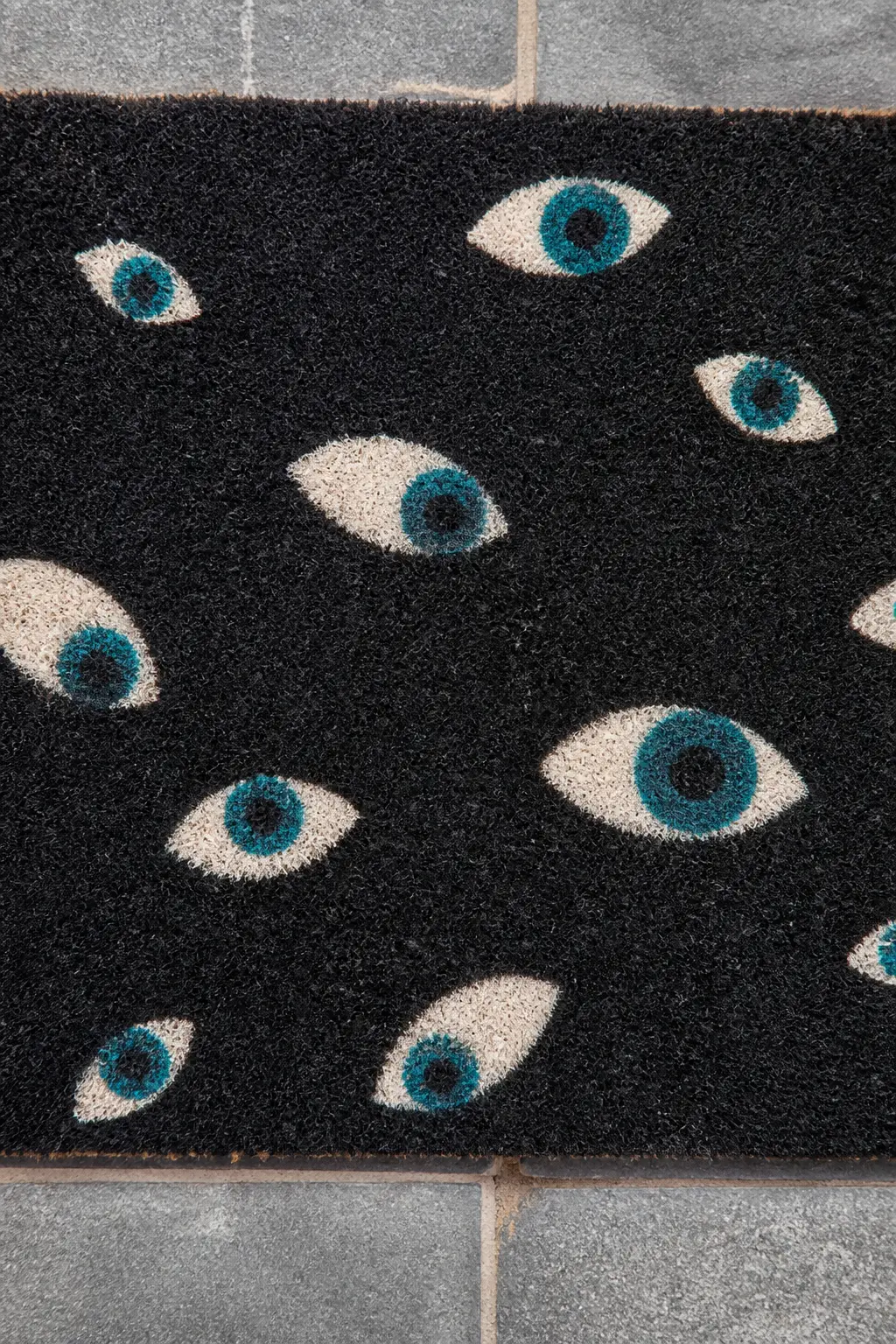 Black Ground, Teal Eyeball Pattern — A black-ground mat with eight to ten scattered eyeball shapes painted in deep teal and white. Diy halloween doormat