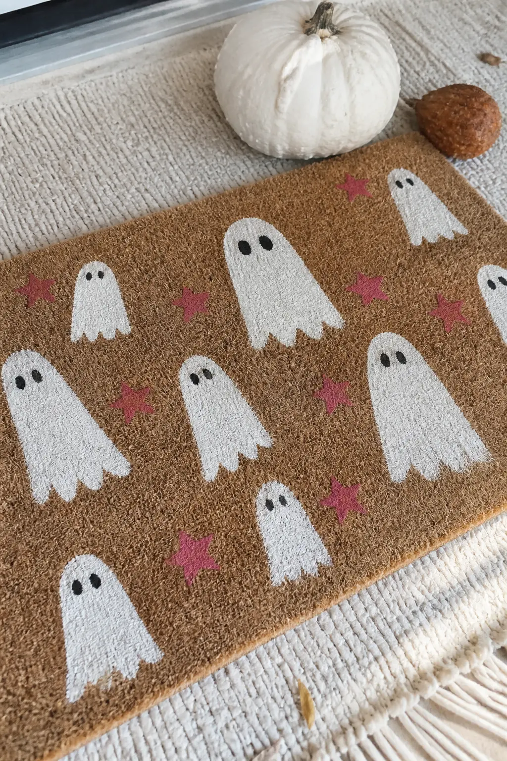 Ghost Parade with Pink Star Accents — Five or six rounded ghost shapes in chalky white, scattered across the mat in no particular order, each with two small