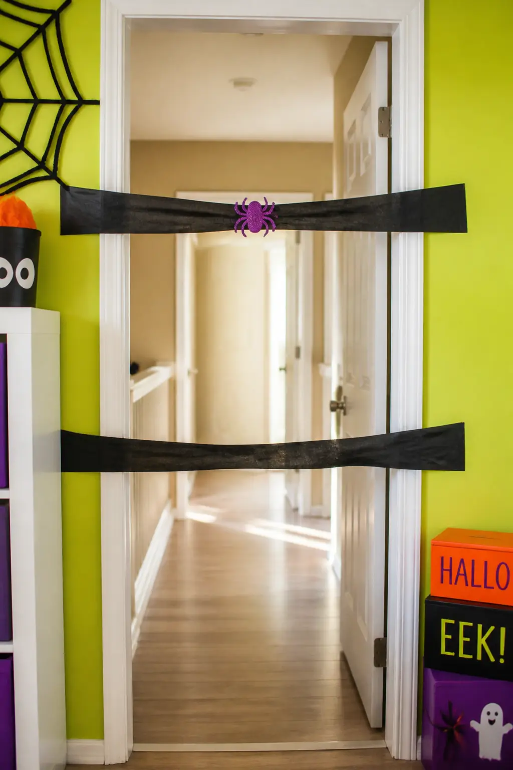 Crepe Paper Spider Web Limbo — Stretch two horizontal lines of black crepe paper across a doorway at different heights, the lower one at about hip height for