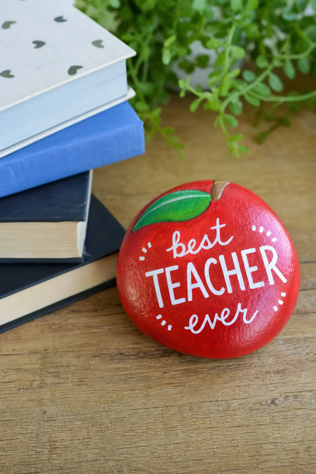 Teacher Apple Gift Stones — A round stone painted red with a small green leaf and stem makes a classic teacher gift that sits on a desk long after the flowers