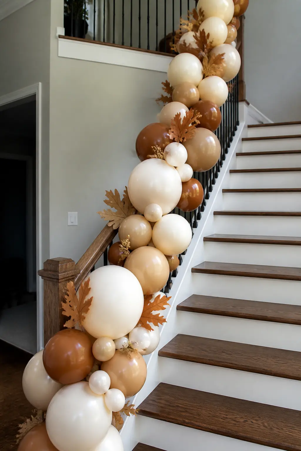 Caramel and Cream Garland Along a Stair Banister with Dried Leaves — Wind a caramel and cream balloon garland down the length of a stair banister, attaching it
