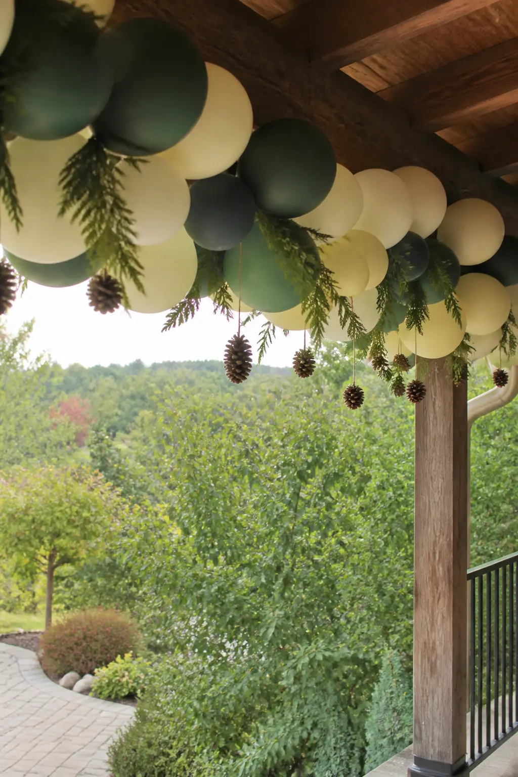 Deep green and Cream Garland Along a Porch Beam with Pinecones — Fix a deep green and cream garland to the underside of a porch beam, running it the full width