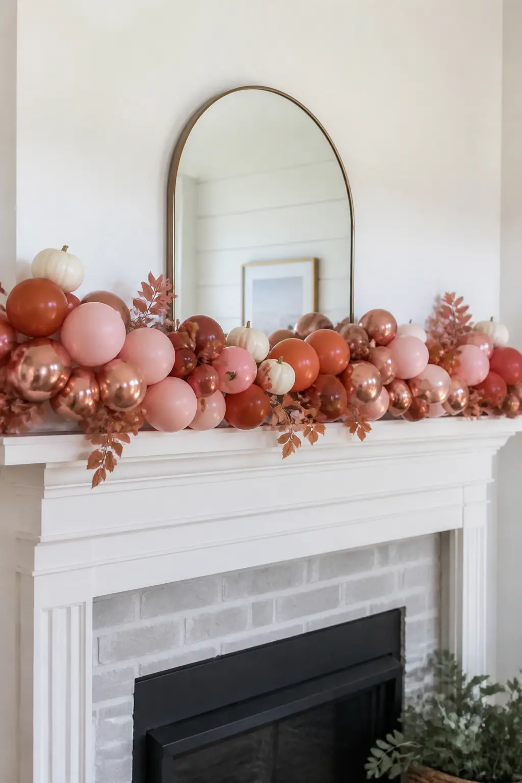 Dusty Pink and Rust Garland Along a Mantel with Mini Pumpkins Wired In — Drape a dusty pink and rust balloon garland along a mantelshelf, anchoring it at each
