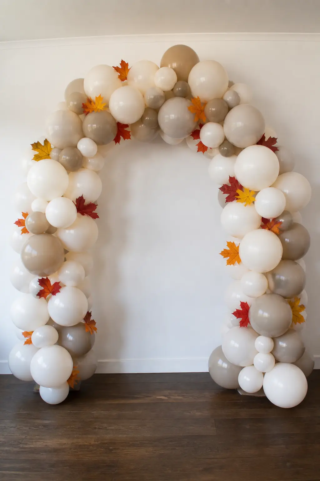 Neutral Arch with the Colour Only in Real Autumn Leaves Pushed Through — Build an arch entirely in sand, ivory and light taupe balloons, and push fresh autumn