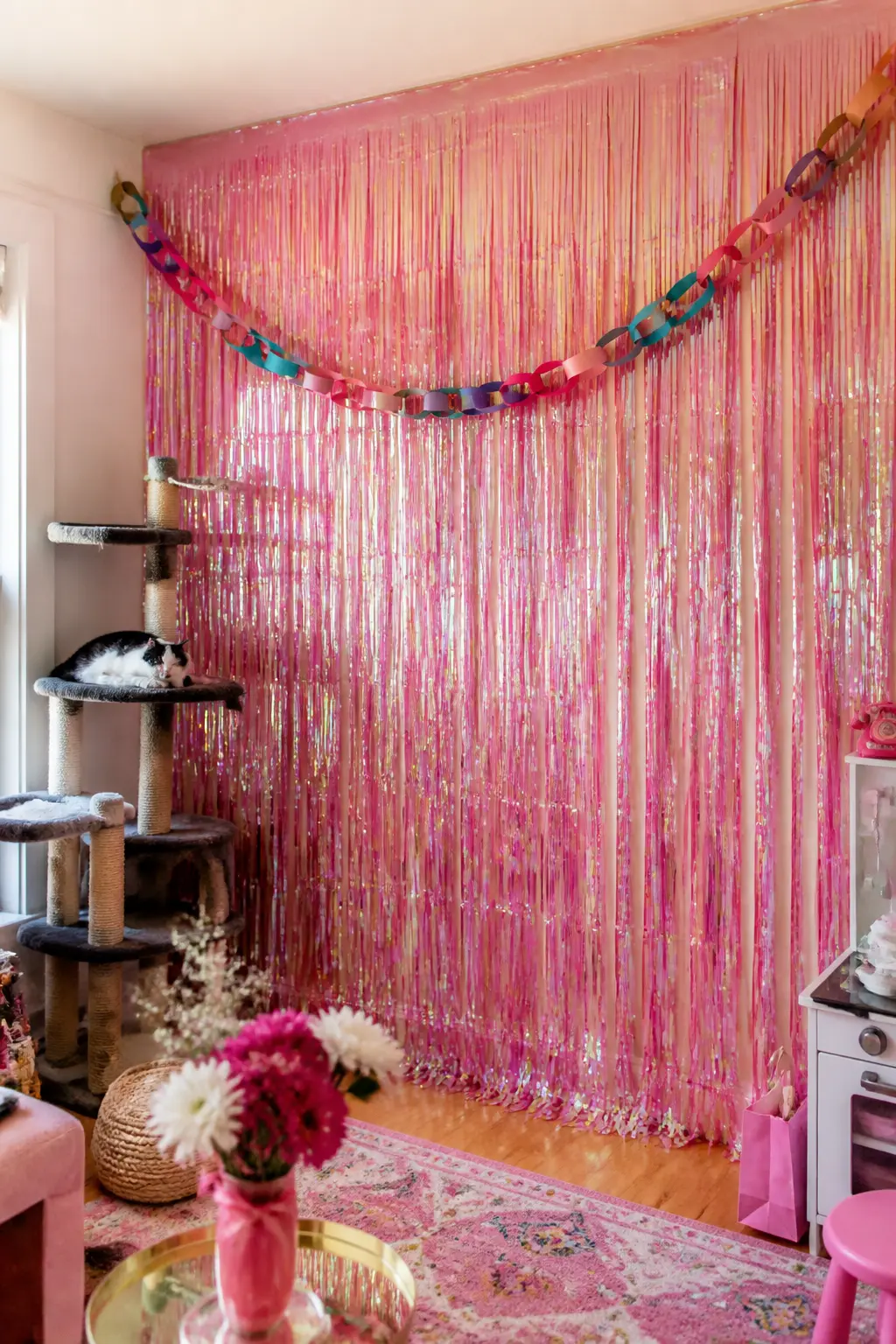 Iridescent Foil Fringe Curtain Wall — A full-length iridescent pink foil fringe curtain hung from a tension rod covers an entire wall in under five minutes and