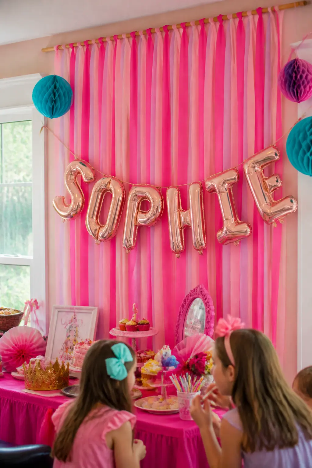 Name Letter Banner on a Crepe Backdrop — Hang vertical strips of pink crepe paper from a dowel rod to create a fringe backdrop, then pin individual foil
