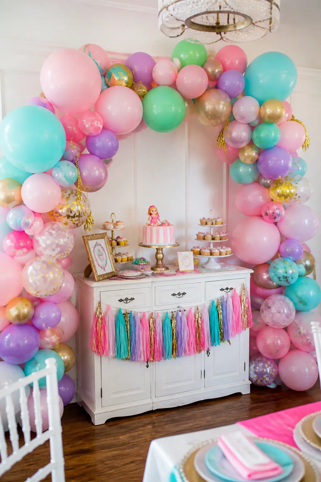 Pastel Balloon Garland Arch — A balloon garland in pink, aqua, lavender and gold organic clusters frames the dessert table or the main backdrop without