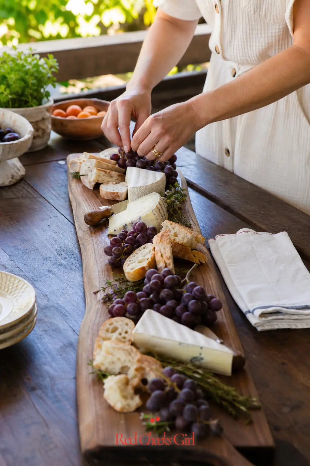 Rustic Cheese and Grape Board Station — A long walnut board loaded with cream cheese wedges, deep purple grapes and torn bread reads as the main event rather