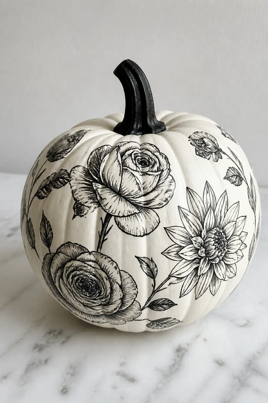 Black Flowers on a White Base — Black on white is the palette of an engraving, and painted flowers in black on a white pumpkin look like a page from a