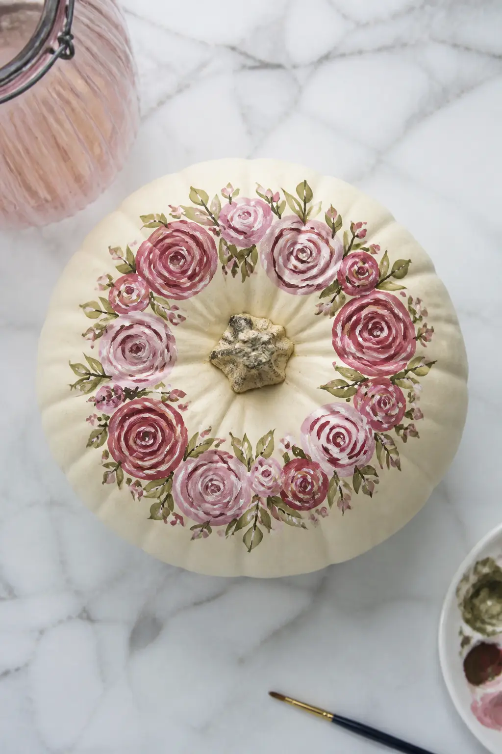A Full Wreath of Roses Around the Stem — A painted rose wreath around the stem is the showpiece of this list. Floral painted pumpkin