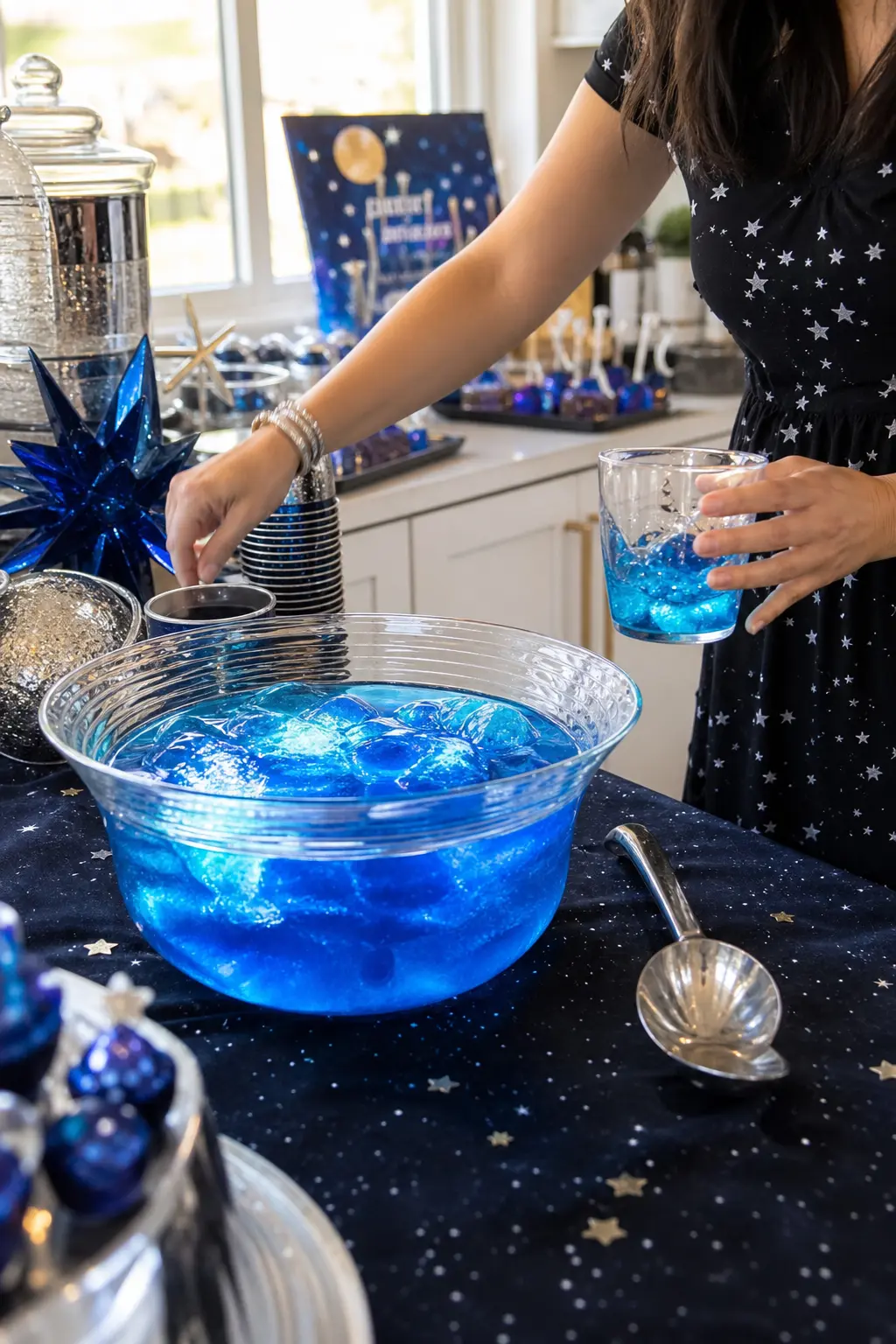Galaxy Punch Bowl Station — An electric blue punch, served from a clear glass bowl with small blue LED cubes dropped in among the ice, glows quietly on the