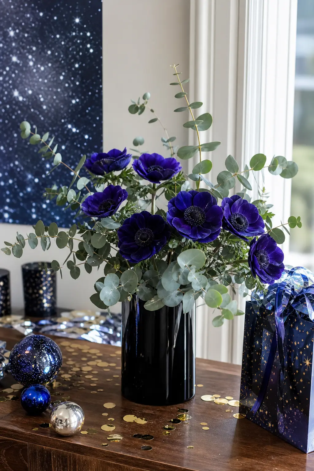 Midnight Floral Centerpiece — Deep indigo anemones, their dark centres already reading as tiny planets, arranged with a few stems of silver dollar eucalyptus