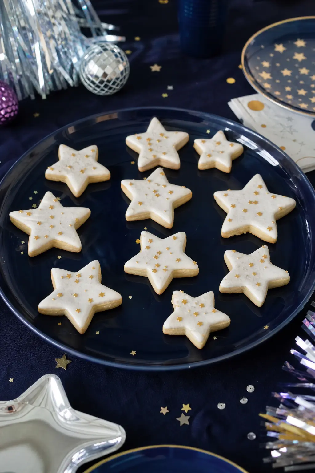 Star Cookie Platter — White royal icing cookies, dotted with gold star sprinkles and set on a plain navy platter, give guests something small to grab without