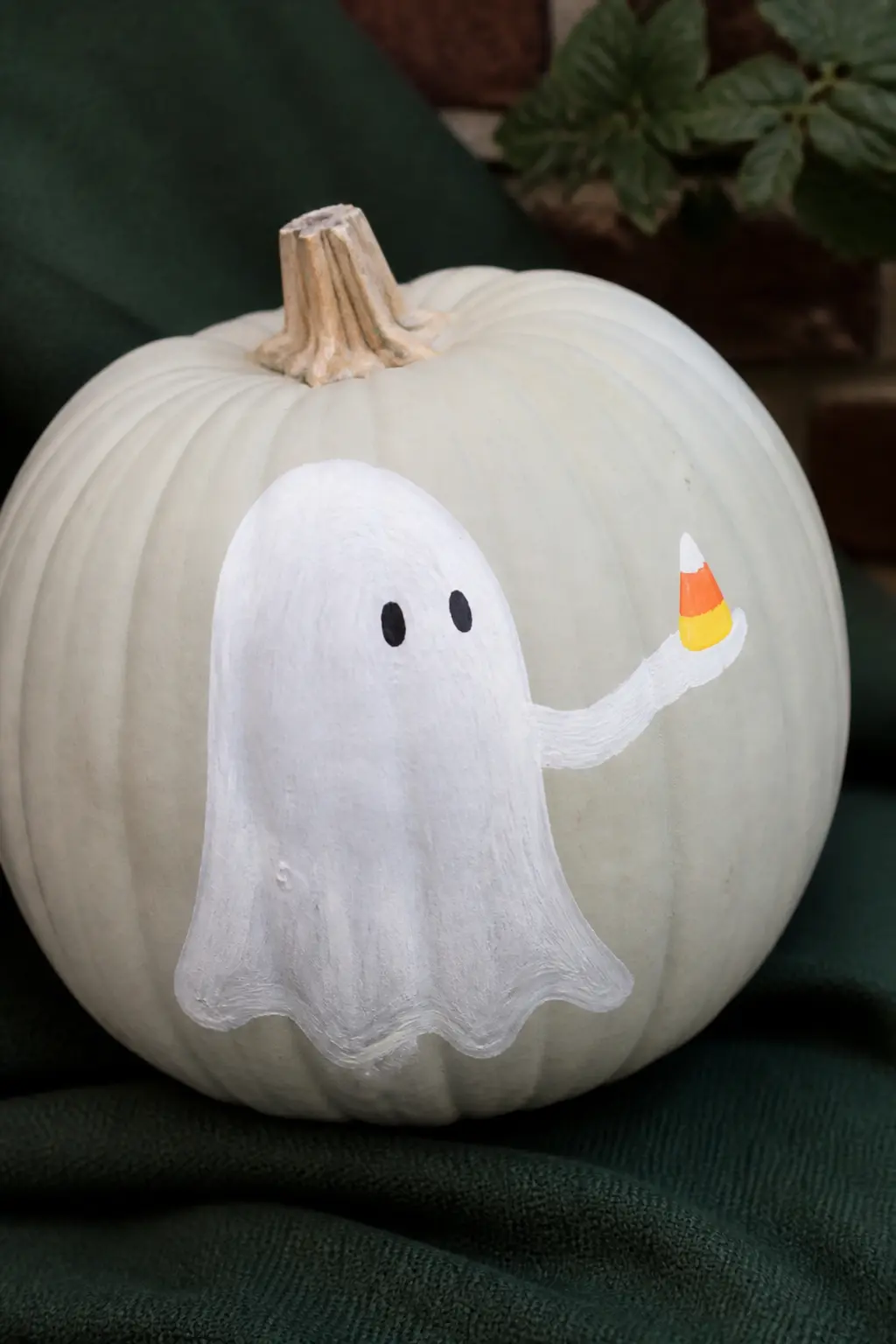 Ghost Holding a Painted Sweet — The ghost holds a small painted candy in its outstretched arm: a lollipop, a candy corn, or a wrapped sweet in any color. Ghost