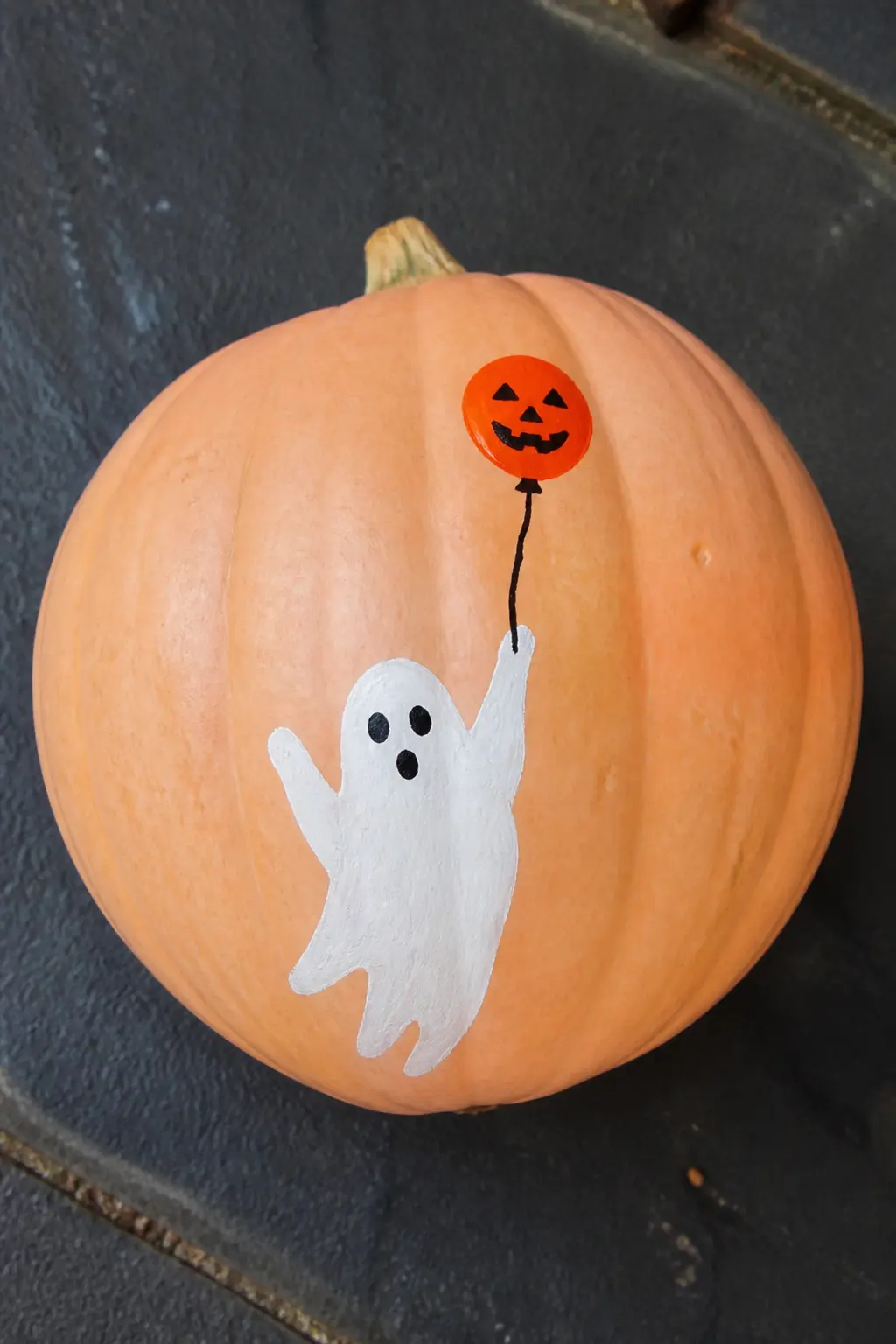 Ghost Holding a Tiny Painted Balloon — One small arm curves up from the ghost's body, and at the end of a thin painted string floats a balloon in any color you