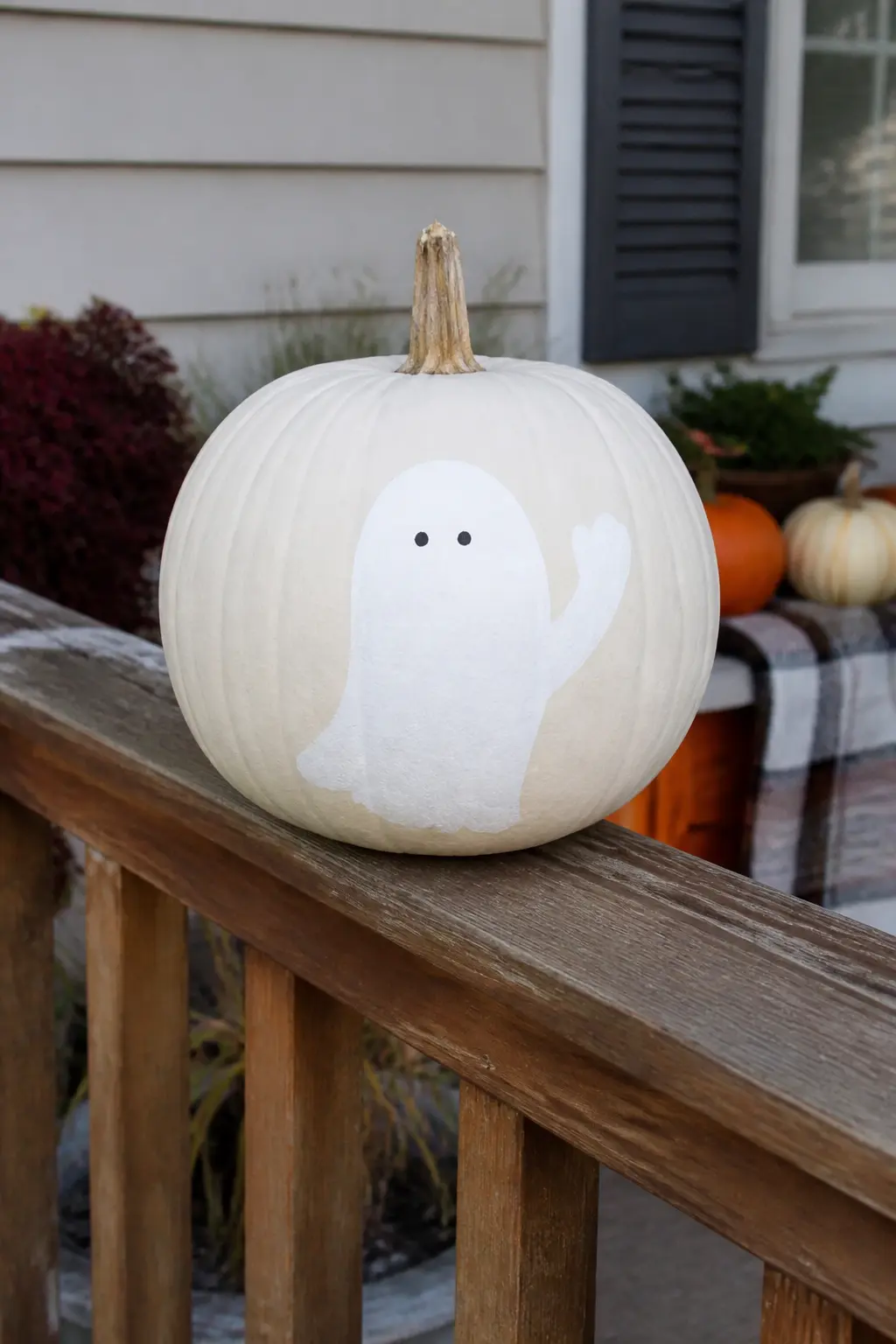Ghost Waving One Arm — One arm extends upward and to the side, the tip curling slightly in a wave. Ghost painted pumpkin