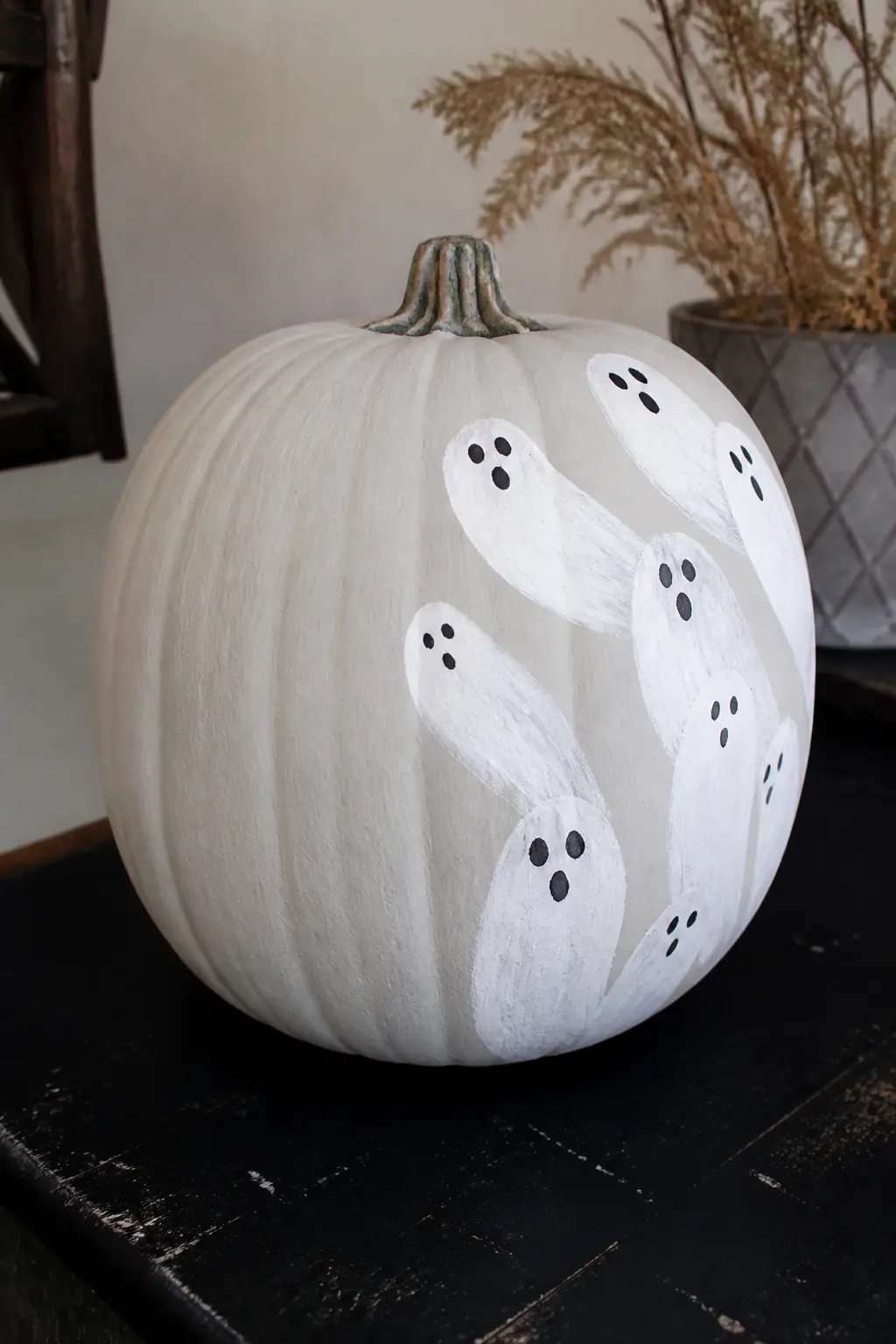 Several Small Ghosts Crowded on One Side — Seven or eight small ghost figures are clustered on one side of the pumpkin, overlapping slightly, all facing the