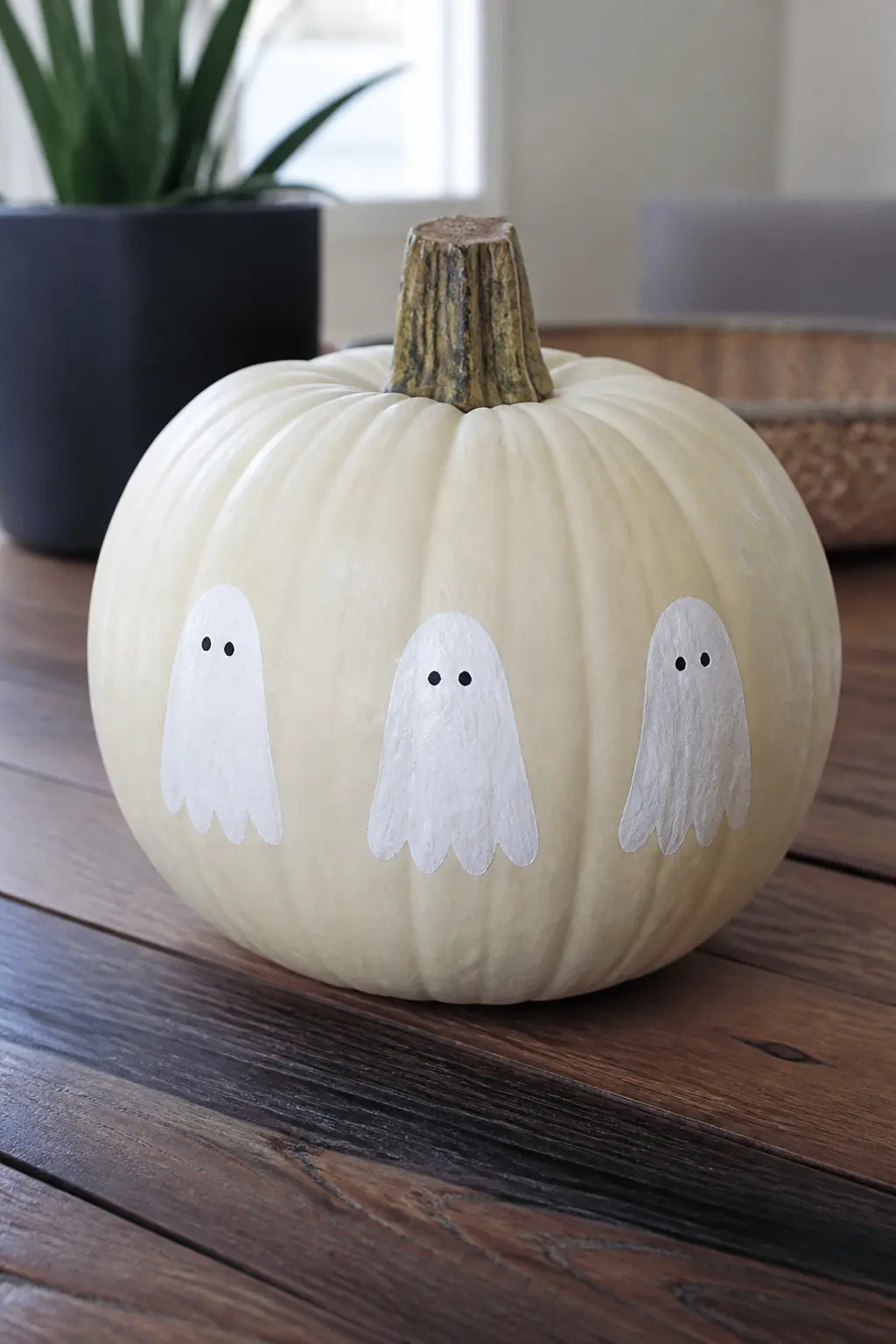 Three Small Ghosts in a Row Around the Middle — Three identical small ghosts, evenly spaced, circle the widest part of the pumpkin like a frieze. Ghost painted
