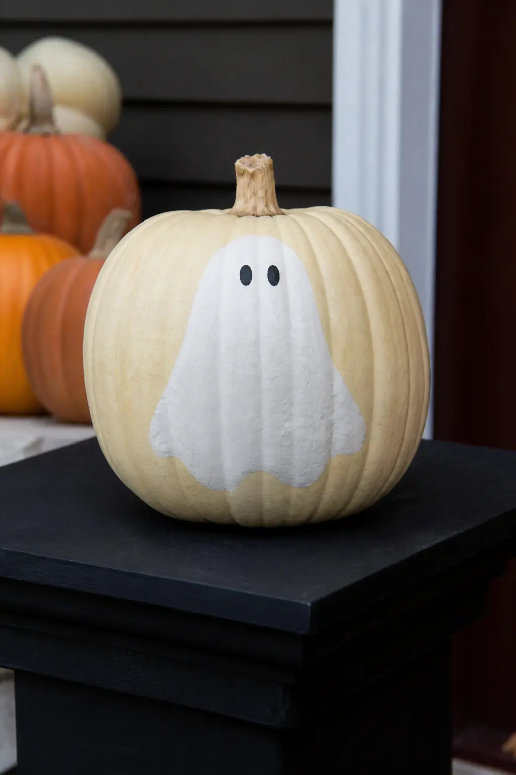 Two Ghosts on Opposite Sides, Facing Away — One ghost is painted on the front of the pumpkin, facing outward. Ghost painted pumpkin