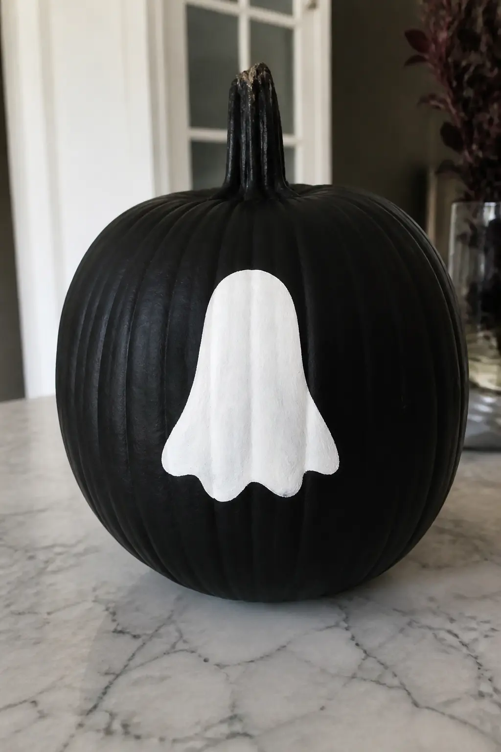 White Ghost on a Black Pumpkin — The pumpkin is painted entirely black first, then a clean white ghost sits on that ground. Ghost painted pumpkin