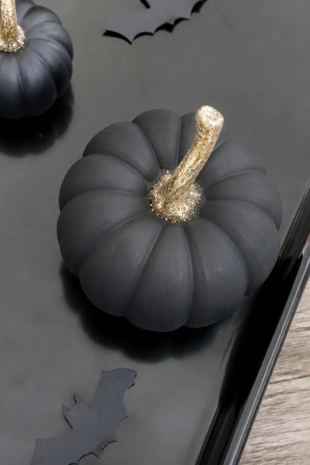 Black Pumpkin With Only the Stem in Gold Glitter — Paint the entire pumpkin matte black including the stem, let it dry fully, then brush glue on the stem only