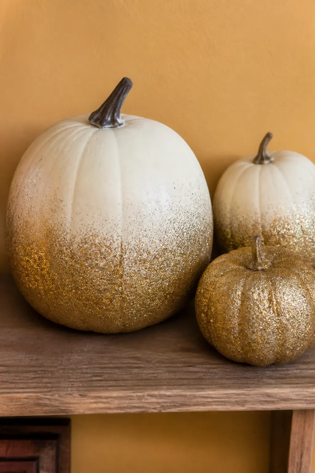 Gold Glitter Gradient From Base to Bare Top — Paint the pumpkin cream or pale gold, then apply glue most heavily at the very base, fading to a dry brush higher