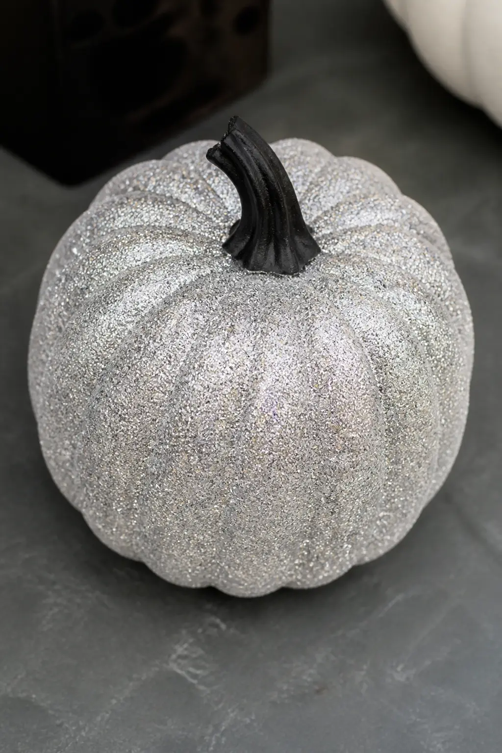 Silver Glitter Pumpkin With a Black Painted Stem — Paint the stem matte black and the body of the pumpkin a mid-grey before applying fine silver glitter over