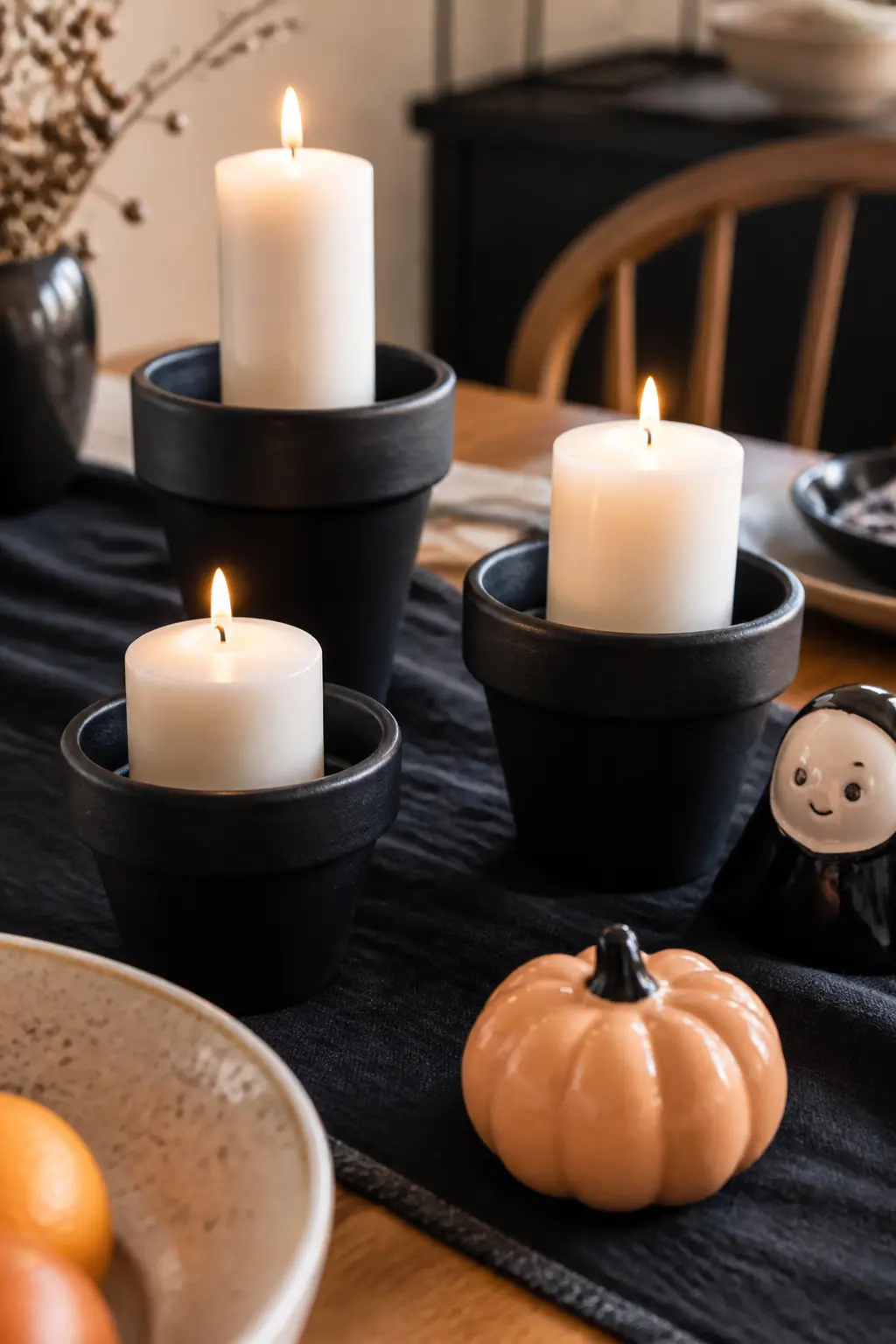 Black-Painted Terracotta Pot Candle Holder — A small terracotta pot, matte black ceramic paint and a pillar candle set inside produce a candle holder that