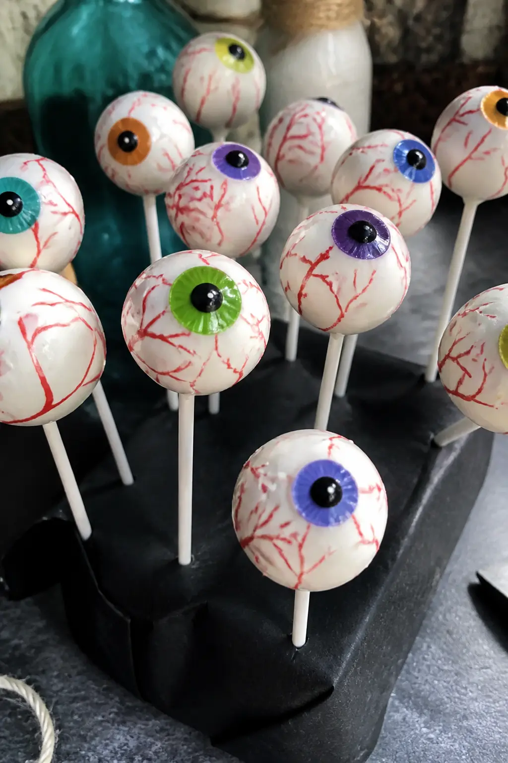 Bloody Eyeball Cake Pops — Dip cake pop rounds in white candy melt coating, let them set, then paint a coloured iris circle and black pupil on each one using