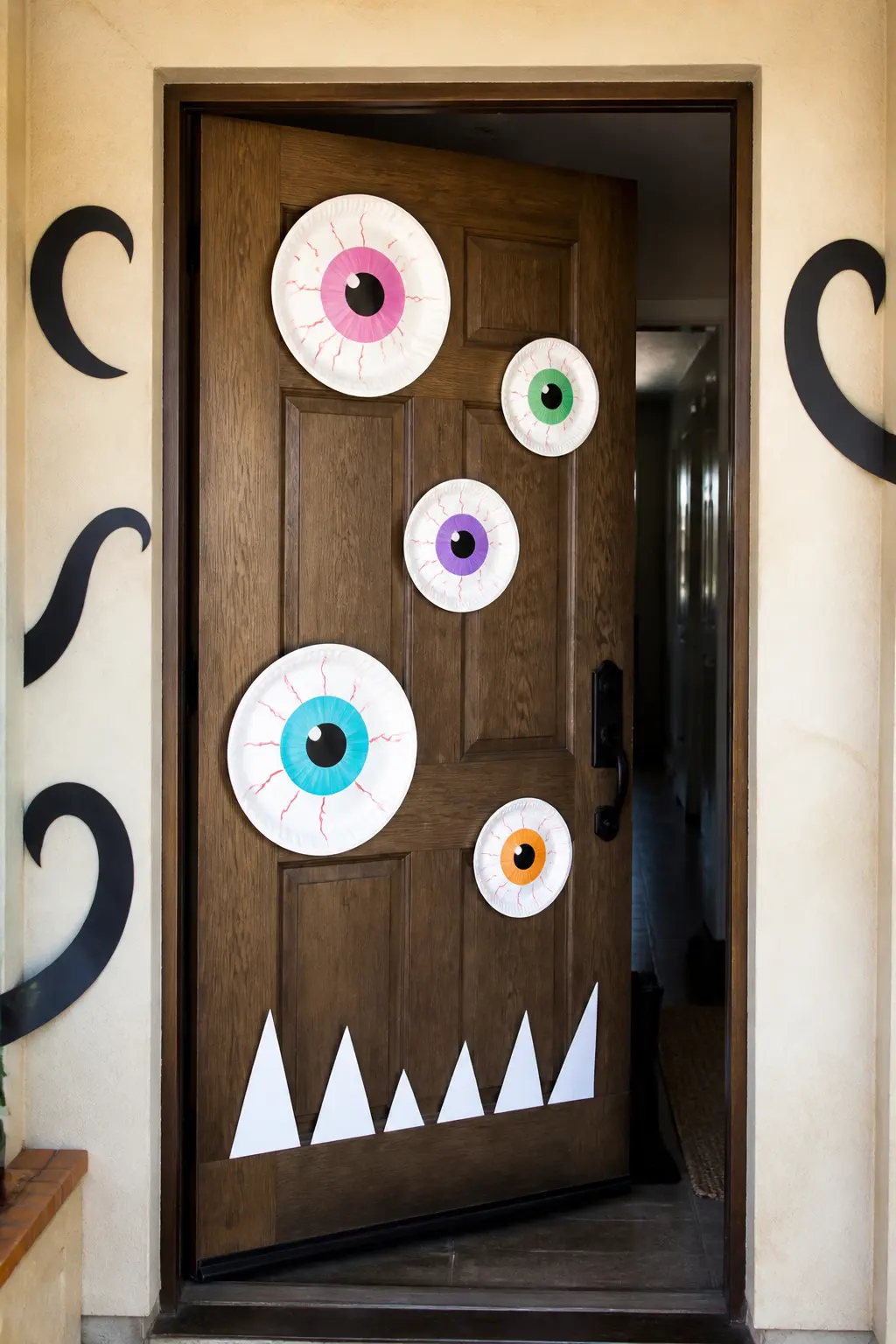 Monster Face Front Door — Cover a front door in paper-plate eyeballs, each made from two nested plates (one larger white plate as the white of the eye, one