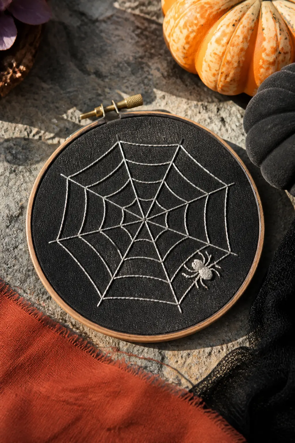Spider Web on Black Linen — A geometric spider web in cream or bone-white thread on black linen: straight-stitch spokes radiating from a centre point, with