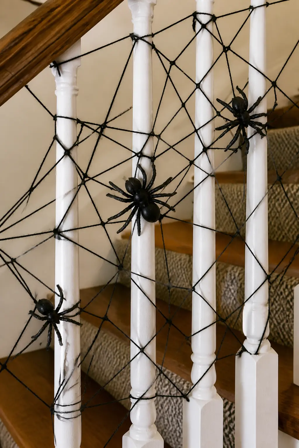 Cobweb Yarn Garland with Resin Spiders — Stretch thin black yarn back and forth between the balusters in irregular crossing patterns to create a
