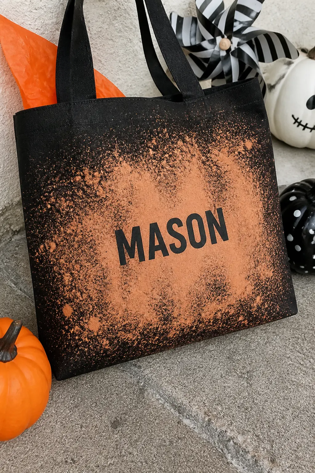 Bleach Spray Splatter With Masked Name — Cut a child's name from adhesive vinyl or contact paper and stick it to the centre of a black canvas bag. Halloween